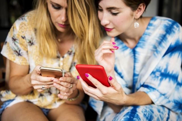 Две девушки смотрят в смартфоны