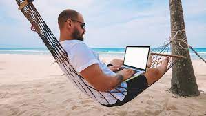 парень в гамаке на пляже с ноутбуком