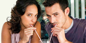 девушка и парень пьют из трубочек с одного бокала